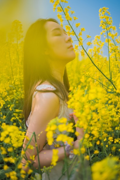 Young woman standing amidst yellow flowering plants on field