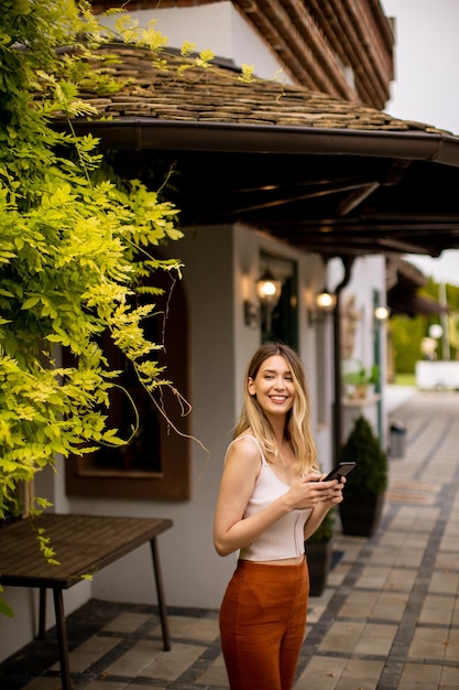 Young woman standing in the backyard and using mobile phone