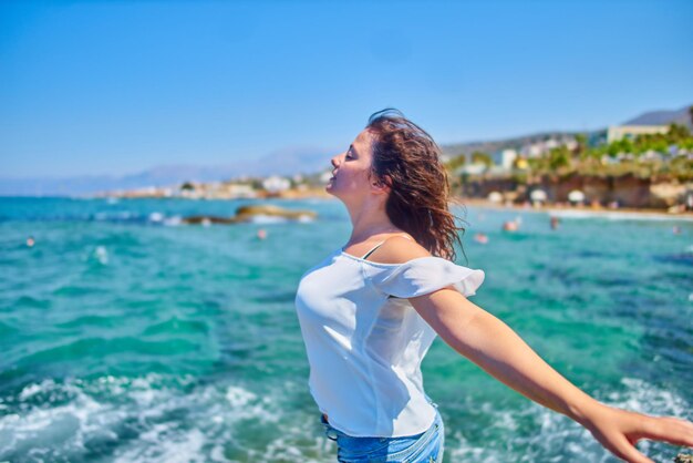 Young woman standing at beach against blue sky