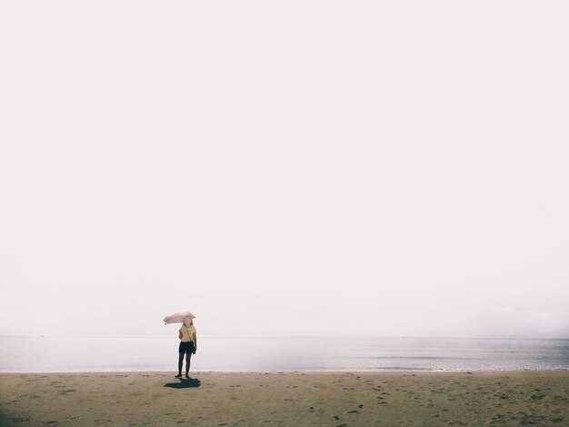 Young woman standing at beach during foggy weather