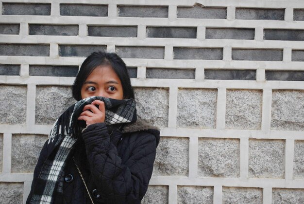 Young woman standing brick wall during winter