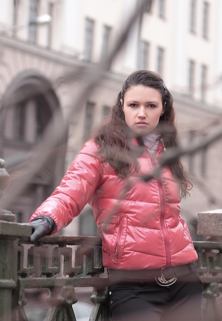 Молодая женщина стоит на мосту в городе