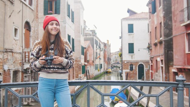 A young woman standing on the bridge holding a camera venice italy