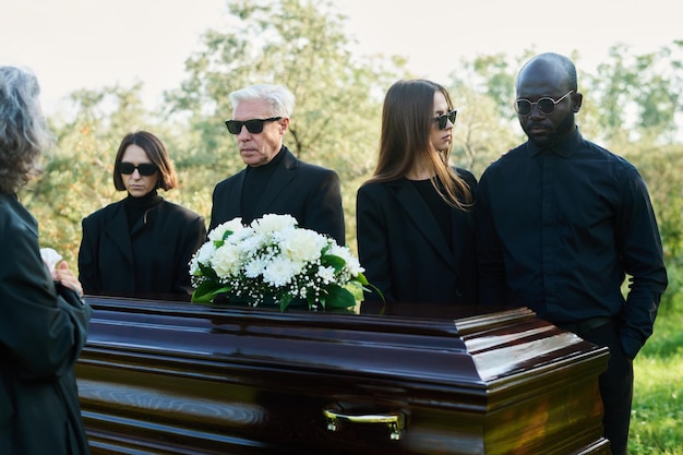 Young woman standing by her grieving husband in mourning clothes