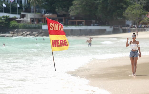 Photo young woman standing by information sign at beach