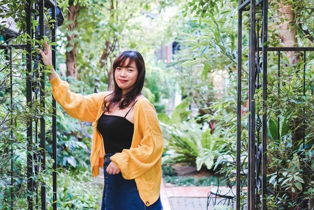 Young woman standing by plants against trees