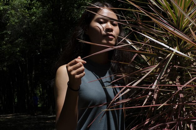 Photo young woman standing by plants in forest