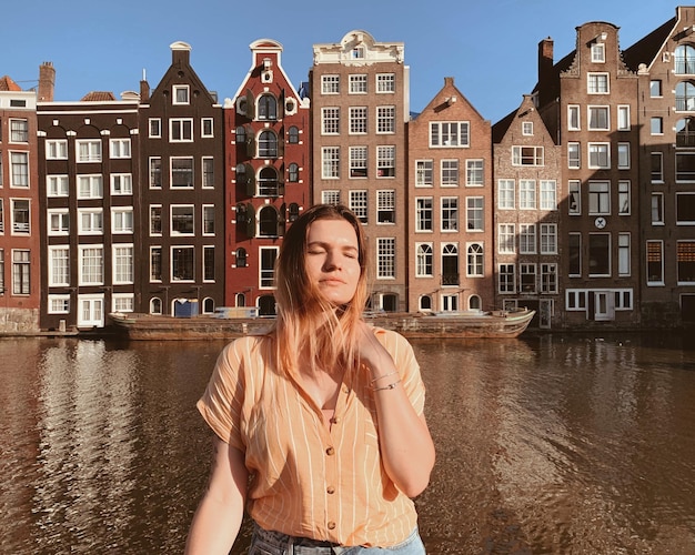 Фото Молодая женщина стоит у реки в городе