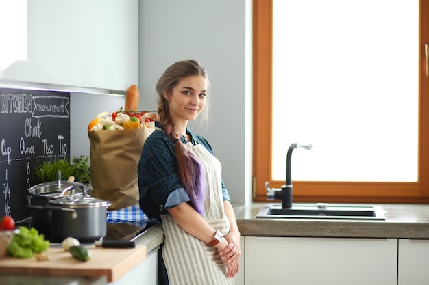 Молодая женщина, стоя у плиты на кухне