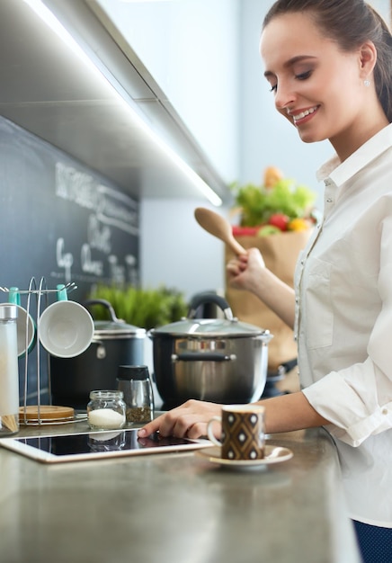 Young woman standing by the stove in the kitchen