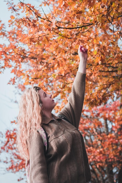 Photo young woman standing by tree during autumn