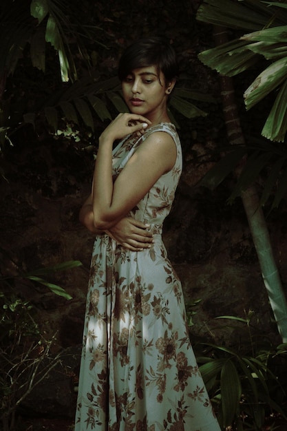 Young woman standing by tree in forest