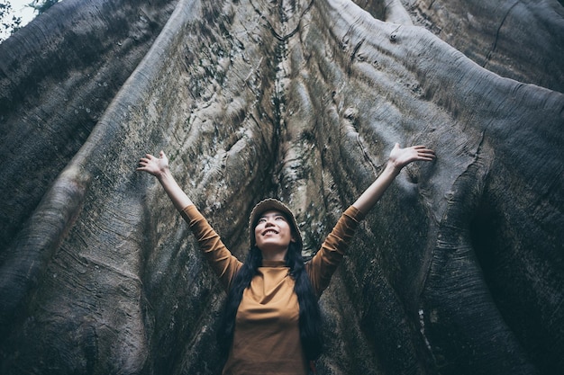 Foto giovane donna in piedi vicino al tronco dell'albero