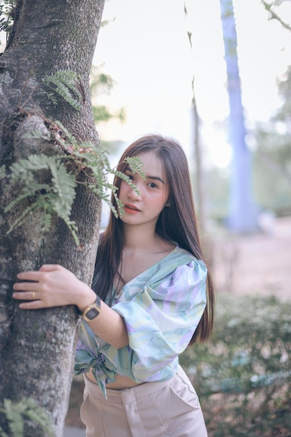 Фото Молодая женщина стоит у ствола дерева
