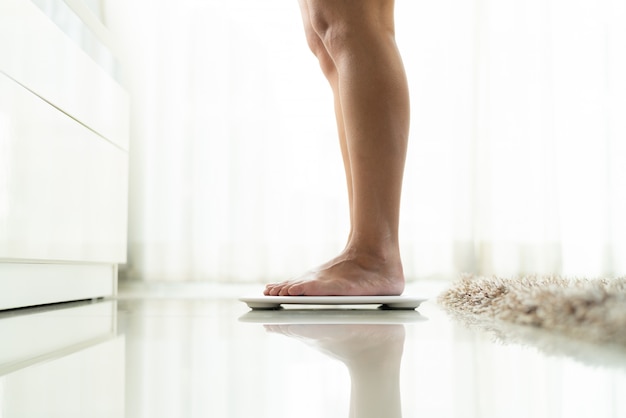 Young woman standing on digital weight scale