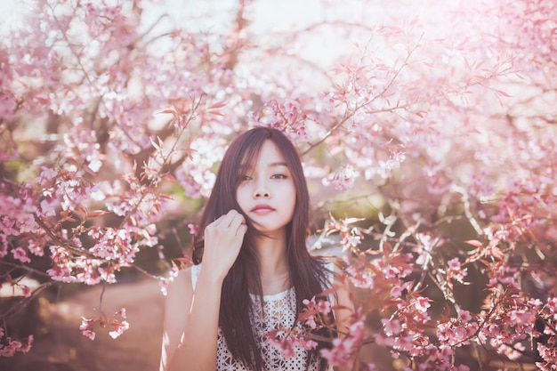 公園の桜の花の前に立っている若い女性
