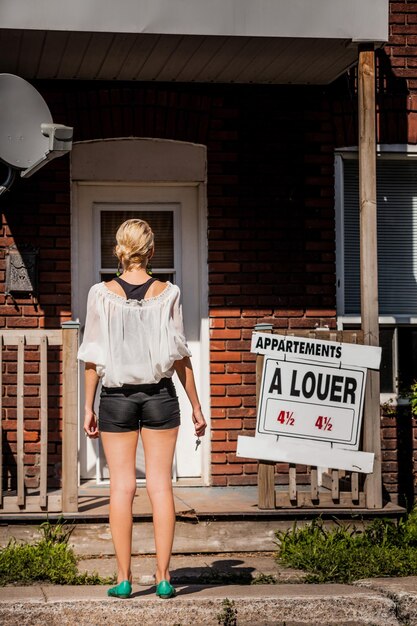 Photo young woman standing in front of her new apartment