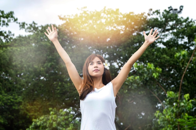 写真 木に背を向けて公園に立っている若い女性