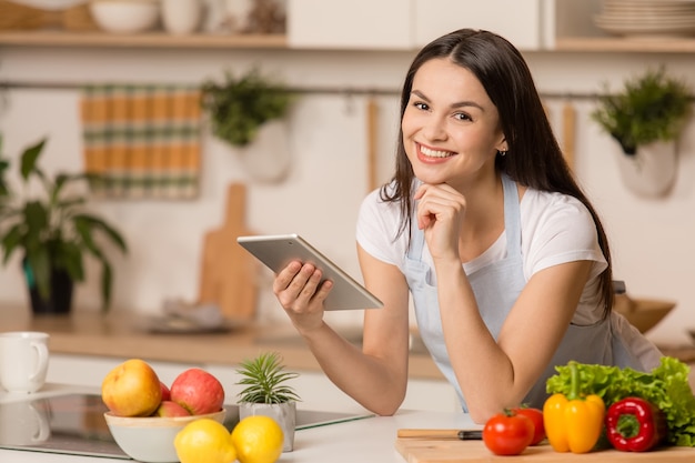 写真 タブレットでキッチンに立っている若い女性