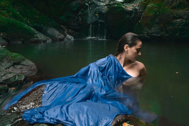 Foto giovane donna in piedi nel lago contro la cascata