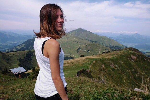 Photo young woman standing on mountain against sky