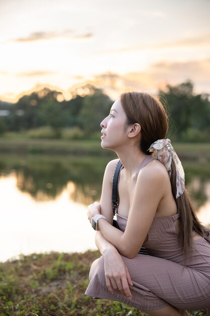Фото Молодая женщина стоит возле озера во время захода солнца красивая природа