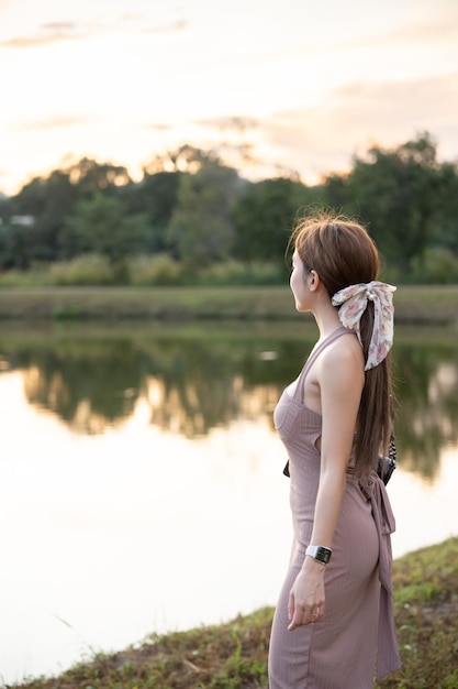 Foto giovane donna in piedi vicino al lago durante il tramonto bellissima natura