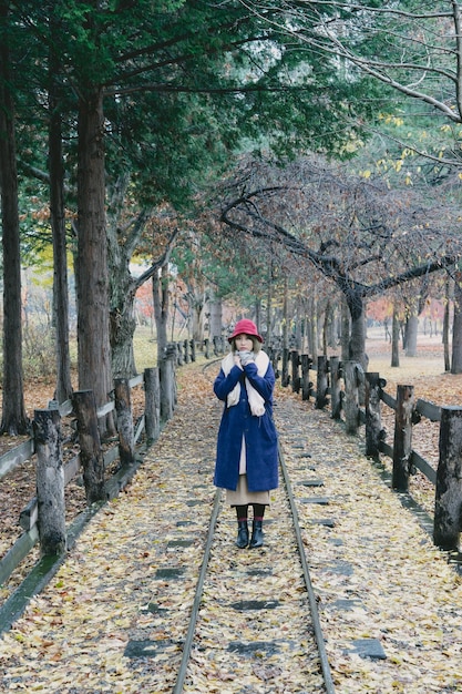 Фото Молодая женщина стоит на железнодорожных рельсах в парке осенью