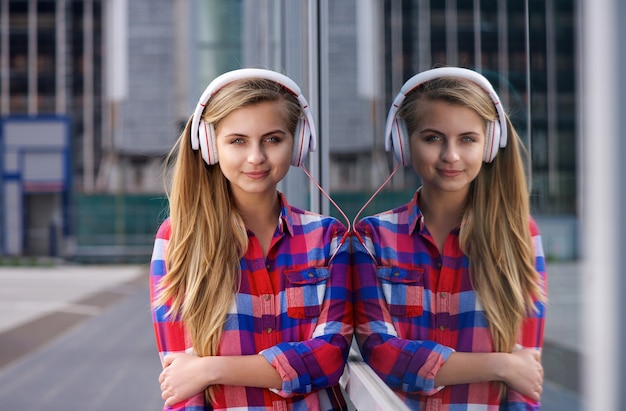 Young woman standing outside listening to music on headphones