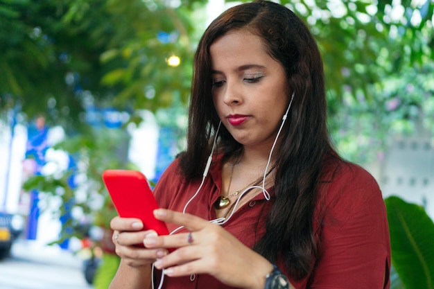 Young woman standing in a park with her smartphone Vlogging concept