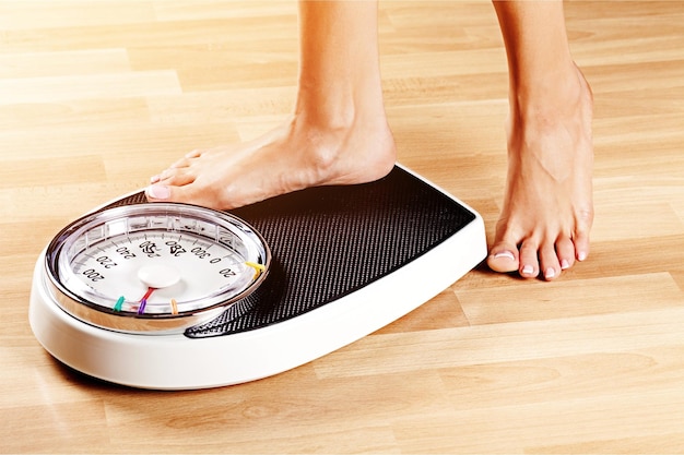 Photo young woman standing on scales with measuring