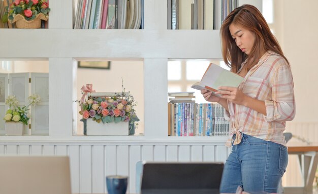 Young woman standing in a serious posture reading.