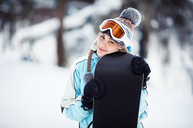 Giovane donna in piedi sulla pista da sci e tenendo il suo snowboard