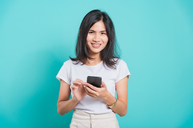 Young woman standing smile holding and using mobile smart phone