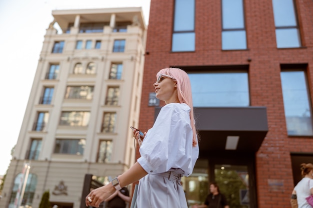 Young woman standing on the street and holding mobile phone