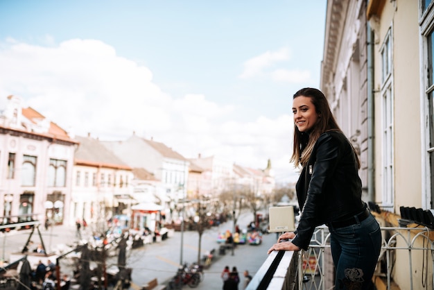 Young woman standing on a terrace over the city street.