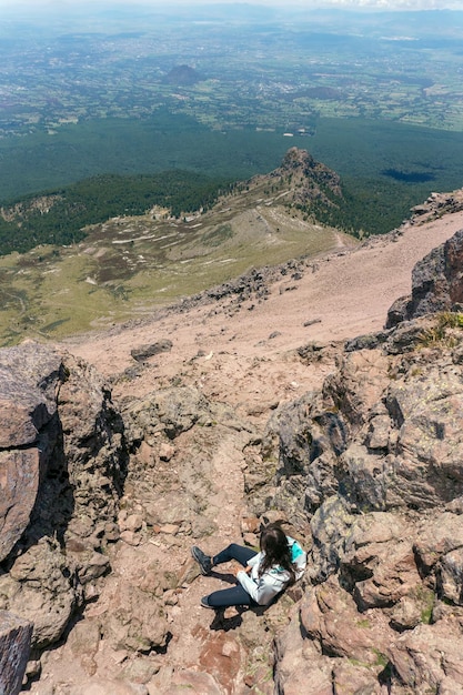 Young woman standing on top of cliff in summer mountains