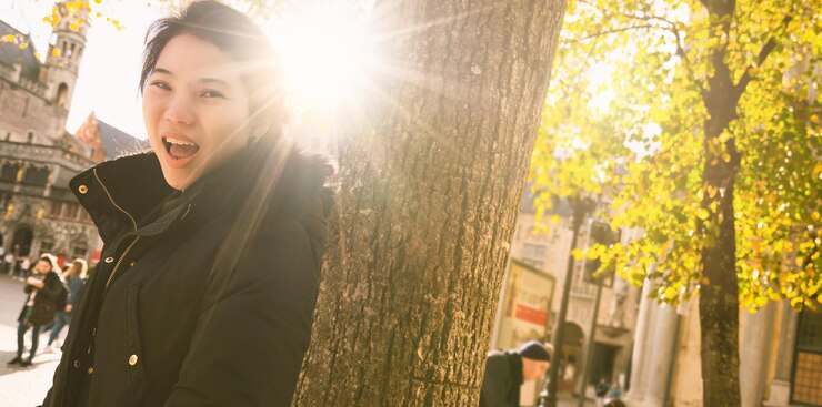 Photo 木の幹の上に立っている若い女性