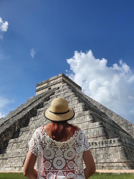 Young woman standing with her back in front of Chichen Itza