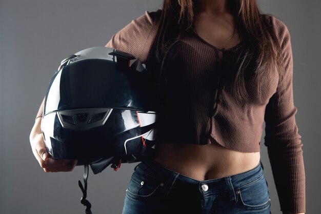Молодая женщина, стоящая с мотоциклетным шлемом