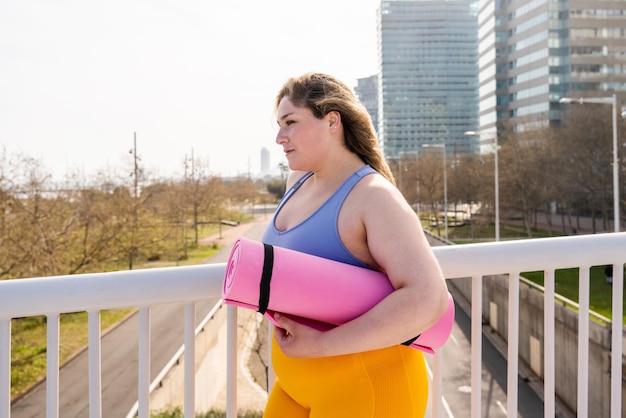 Young woman standing with yoga mat