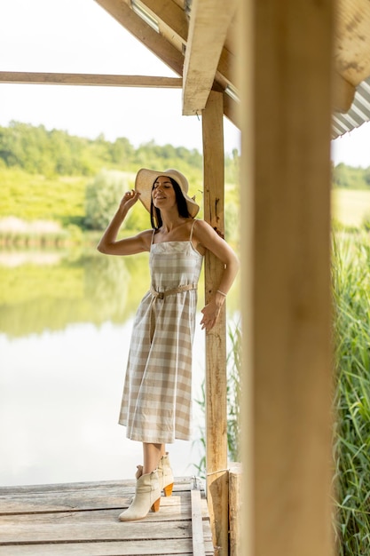 Young woman standing on the wooden pier at the calm lake