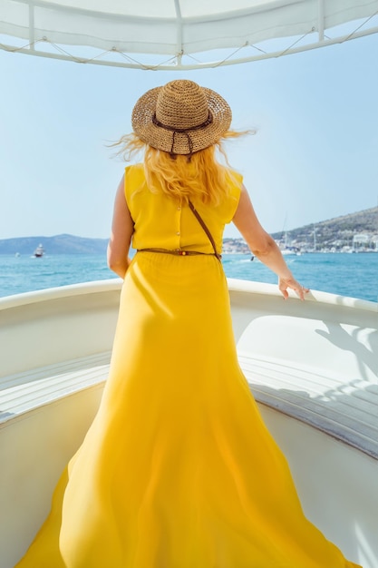 A young woman stands on the bow of a small ship boat and looks into the distance Boat trip by sea