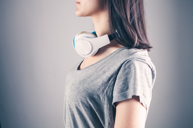 Young woman stands in large headphones on a gray