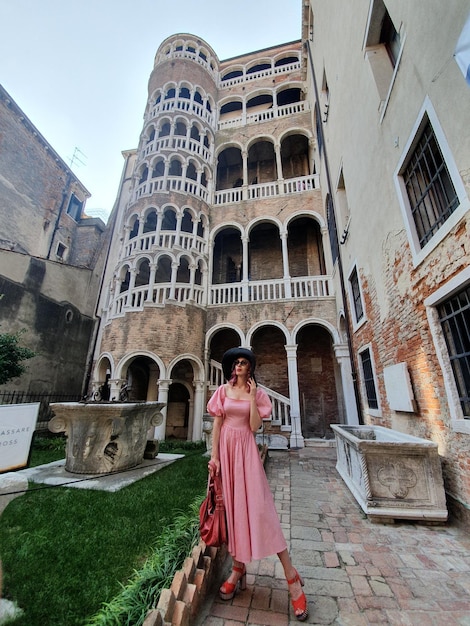 A young woman stands near the Palazzo Contarini del Bovolo