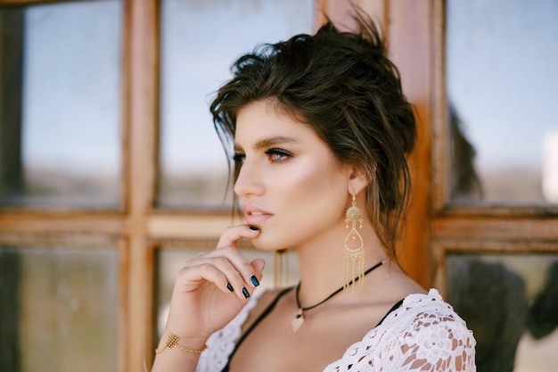 Young woman stands near a wooden glazed door touching her chin with her fingers portrait