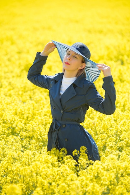 若い女性は菜の花畑に立っています