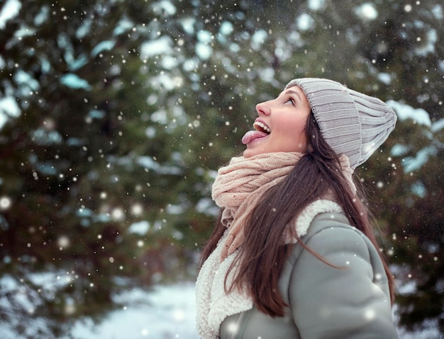 a young woman stands in a winter forest in snowfall with her tongue hanging out