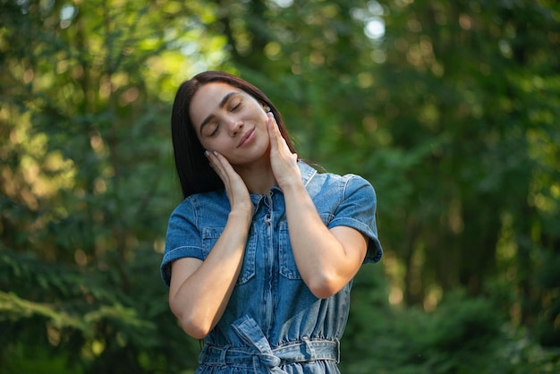 A young woman stands with her eyes closed in the park Fresh air walk healthy lifestyle