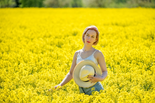 Young woman stands in a yellow field